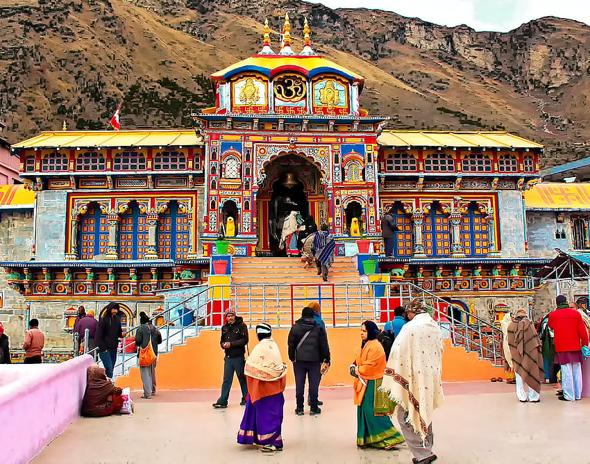 a group of people walking up to a colorful building with Badrinath Temple in the background