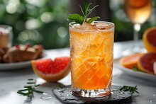 a glass of orange juice with a slice of grapefruit on a table