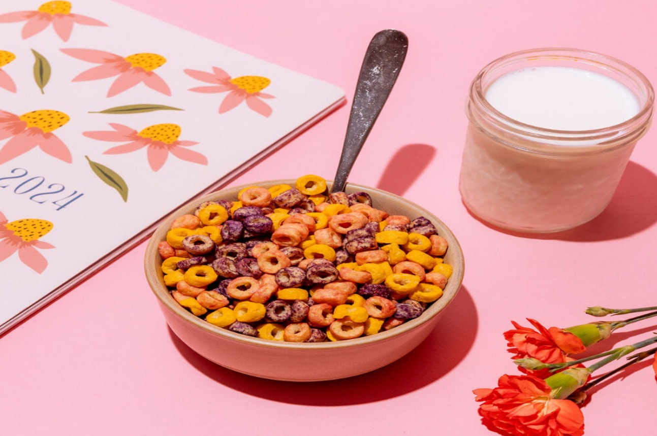 a bowl of cereal with a spoon next to a jar of milk