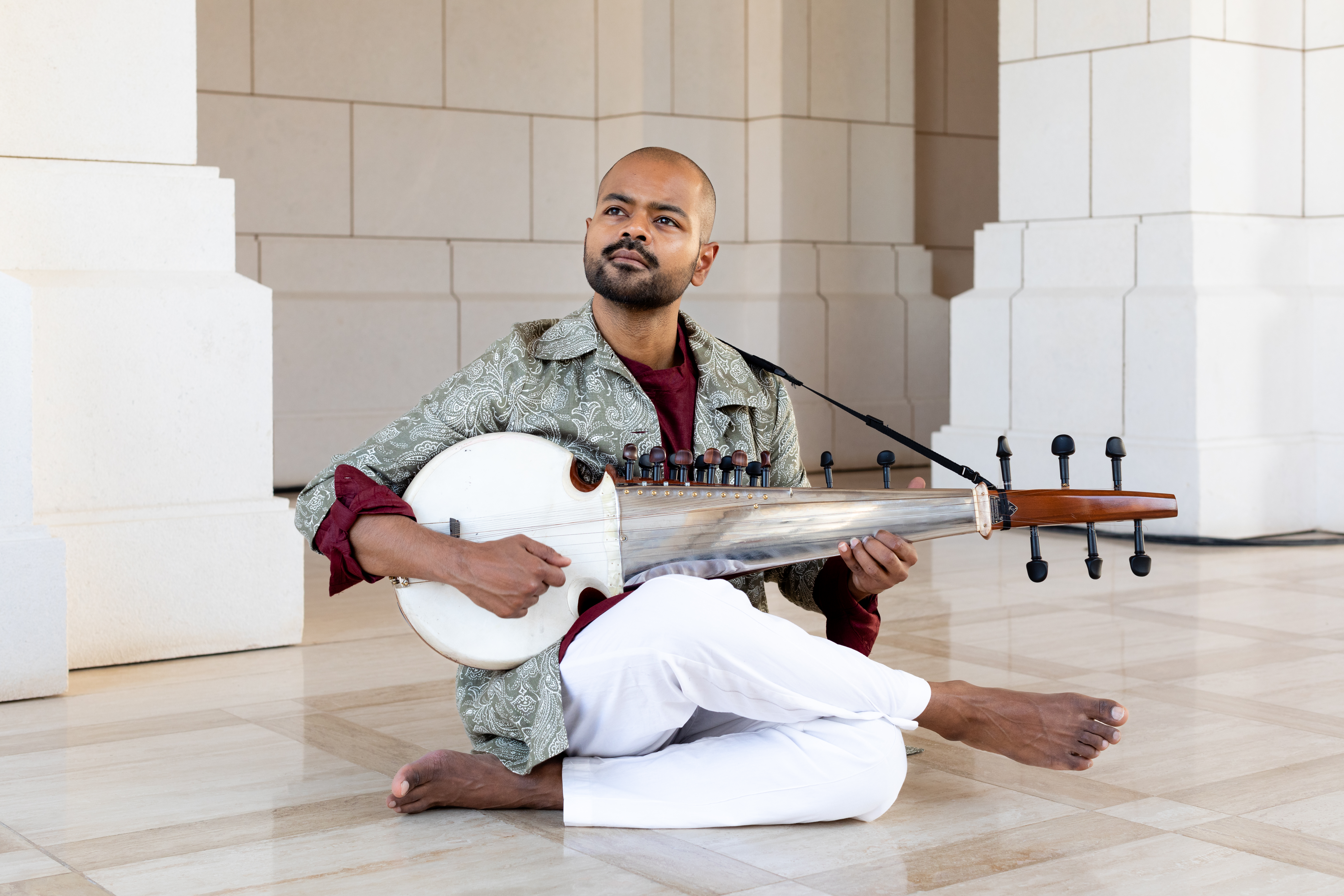 a man sitting on the floor playing a stringed instrument