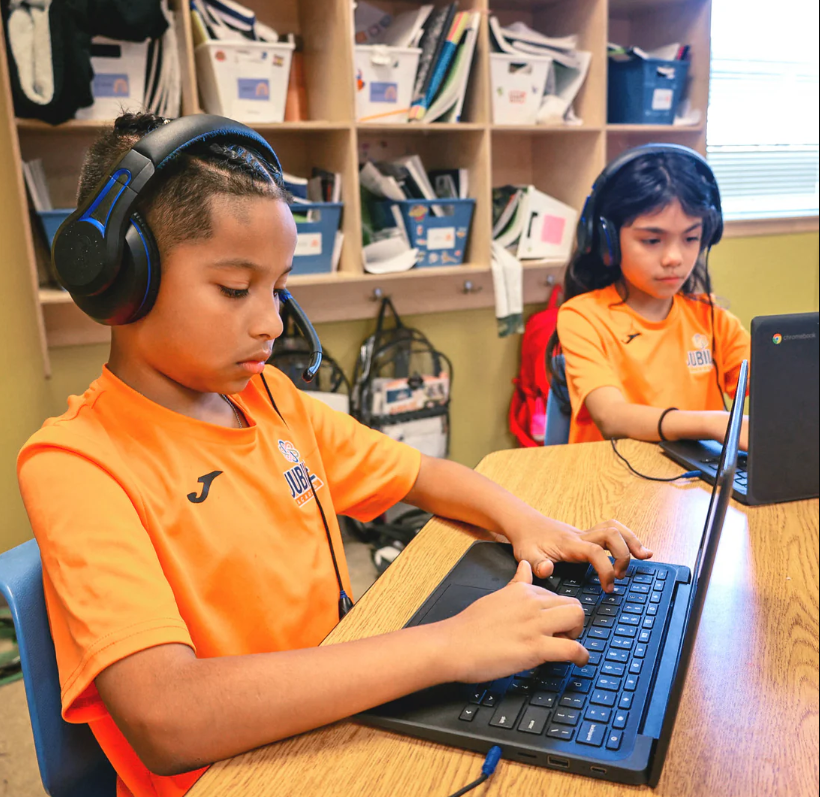 a boy and girl wearing headphones and using a laptop