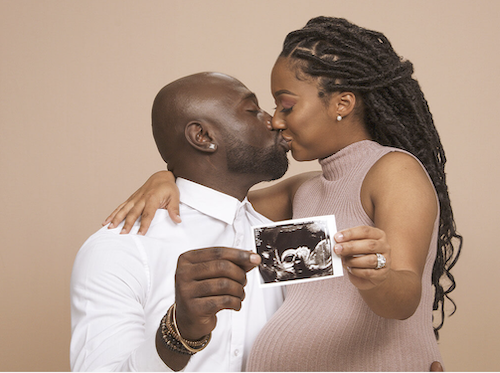 a man and woman kissing while holding an ultrasound picture