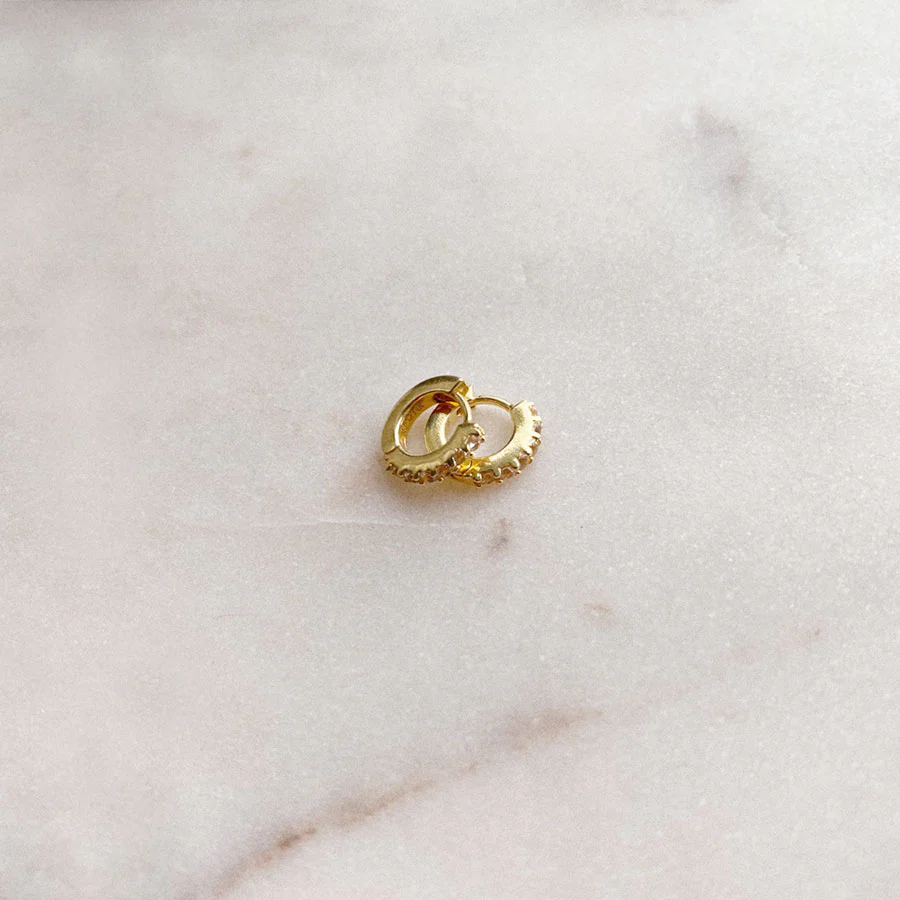 a pair of gold earrings on a marble surface