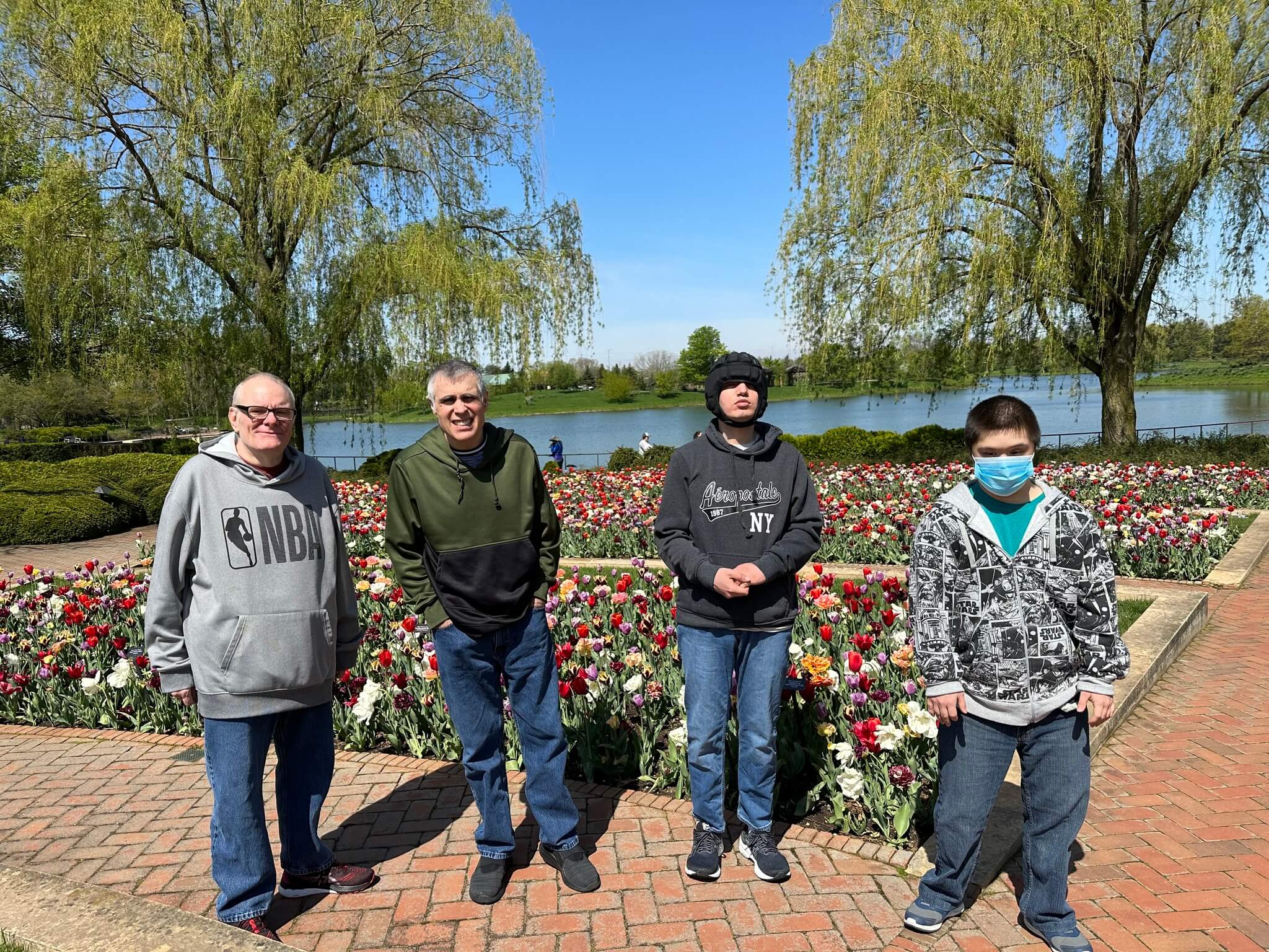 a group of men standing in front of a flower bed