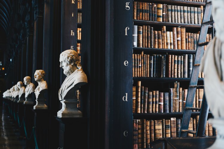 a bookcase with a statue of a man and a bust of a man