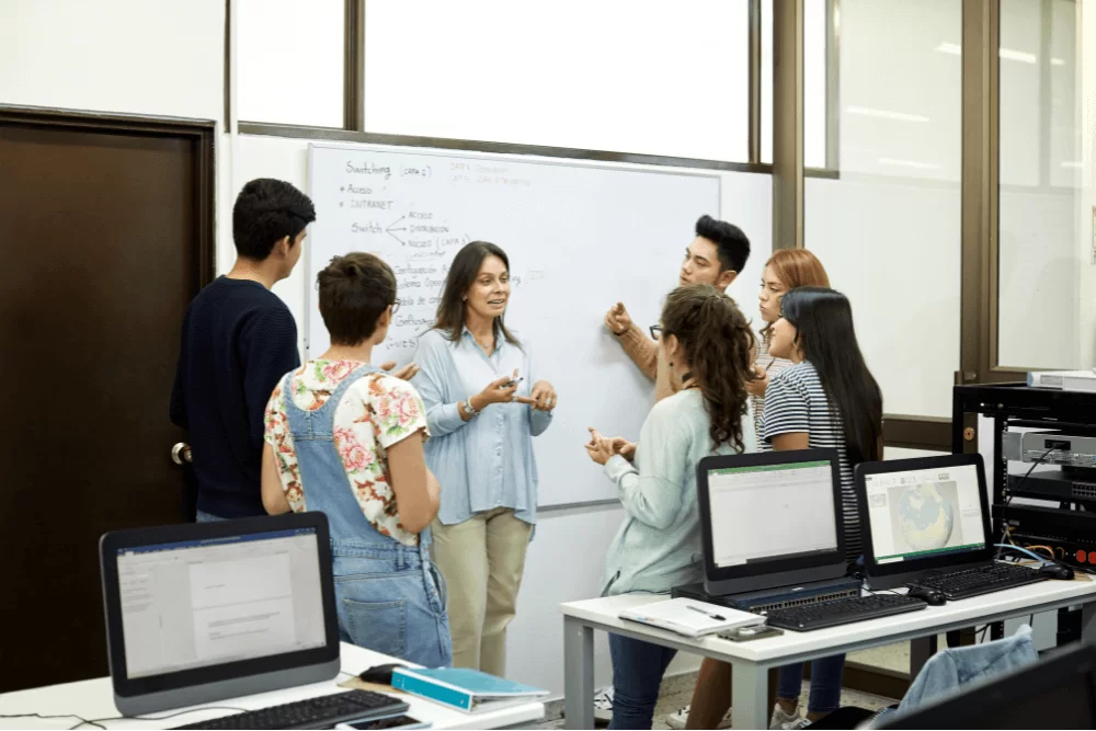 a group of people standing around a whiteboard