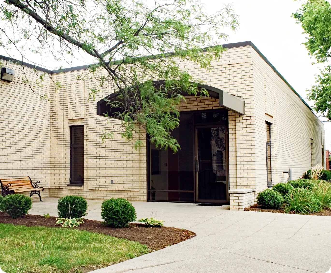 a brick building with a bench and a tree