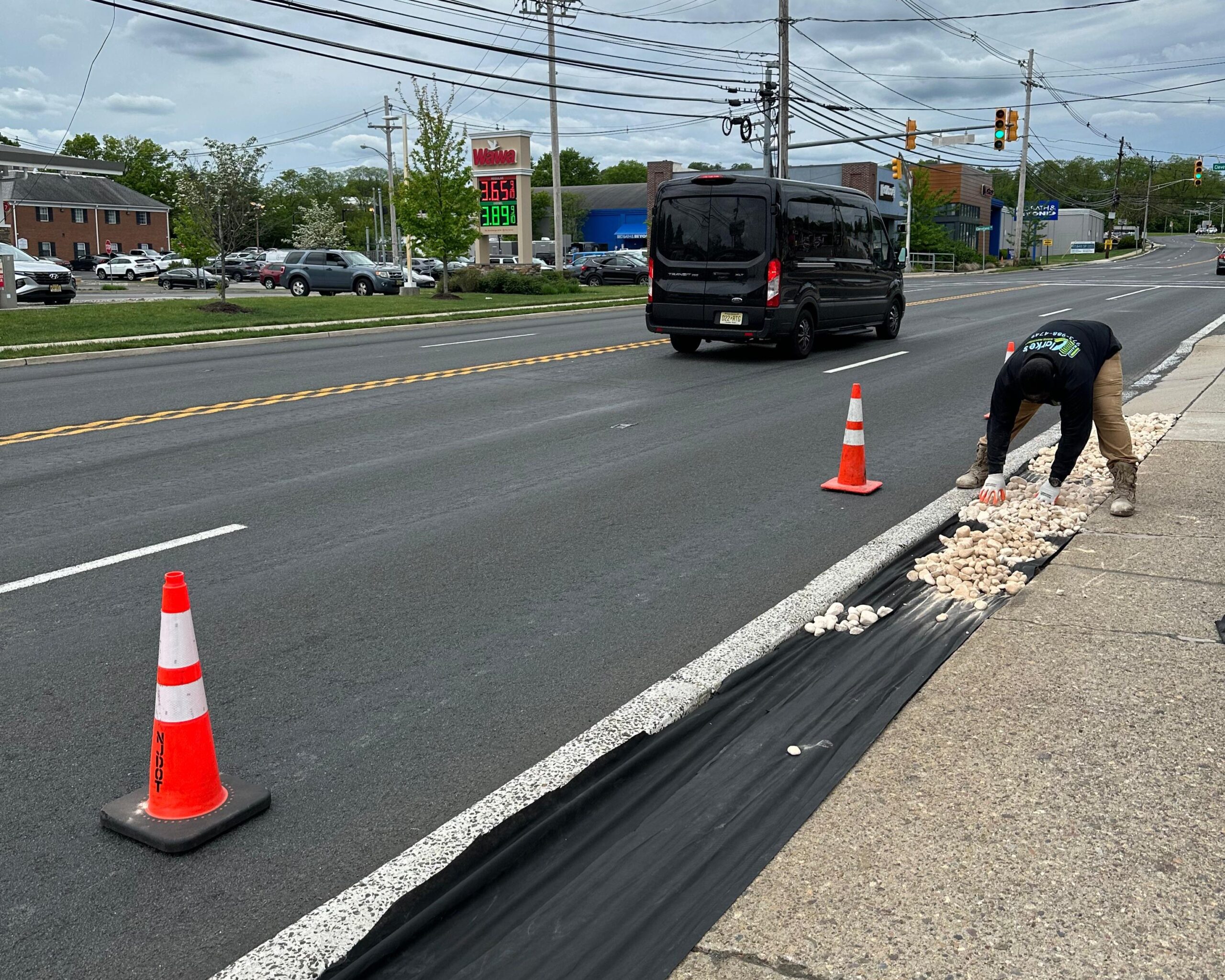 a man digging a curb on a road with orange cones