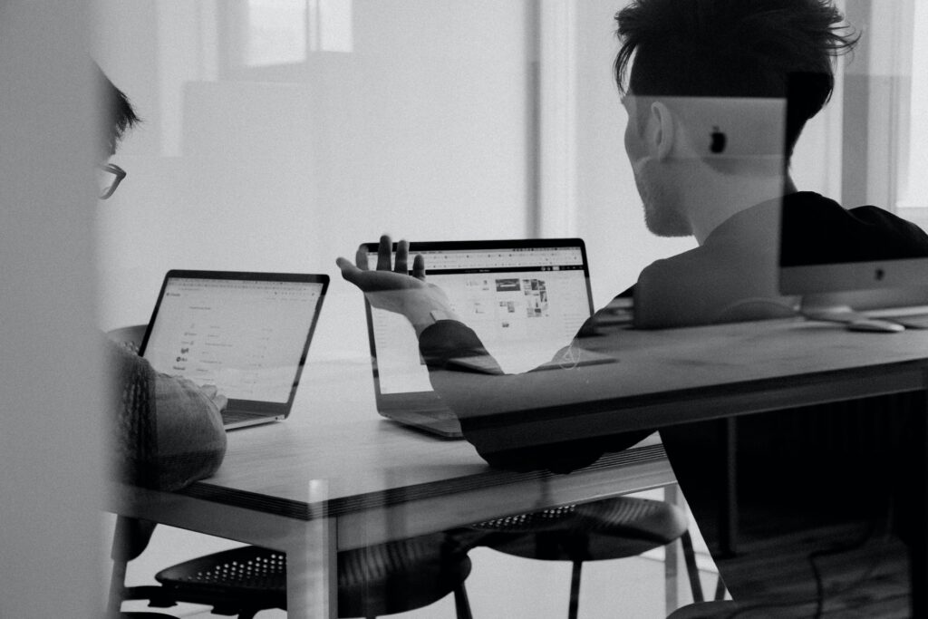 a man sitting at a table with laptops