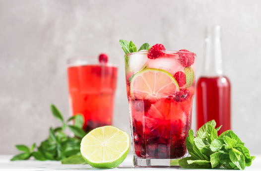 a glass of red drink with fruit and mint