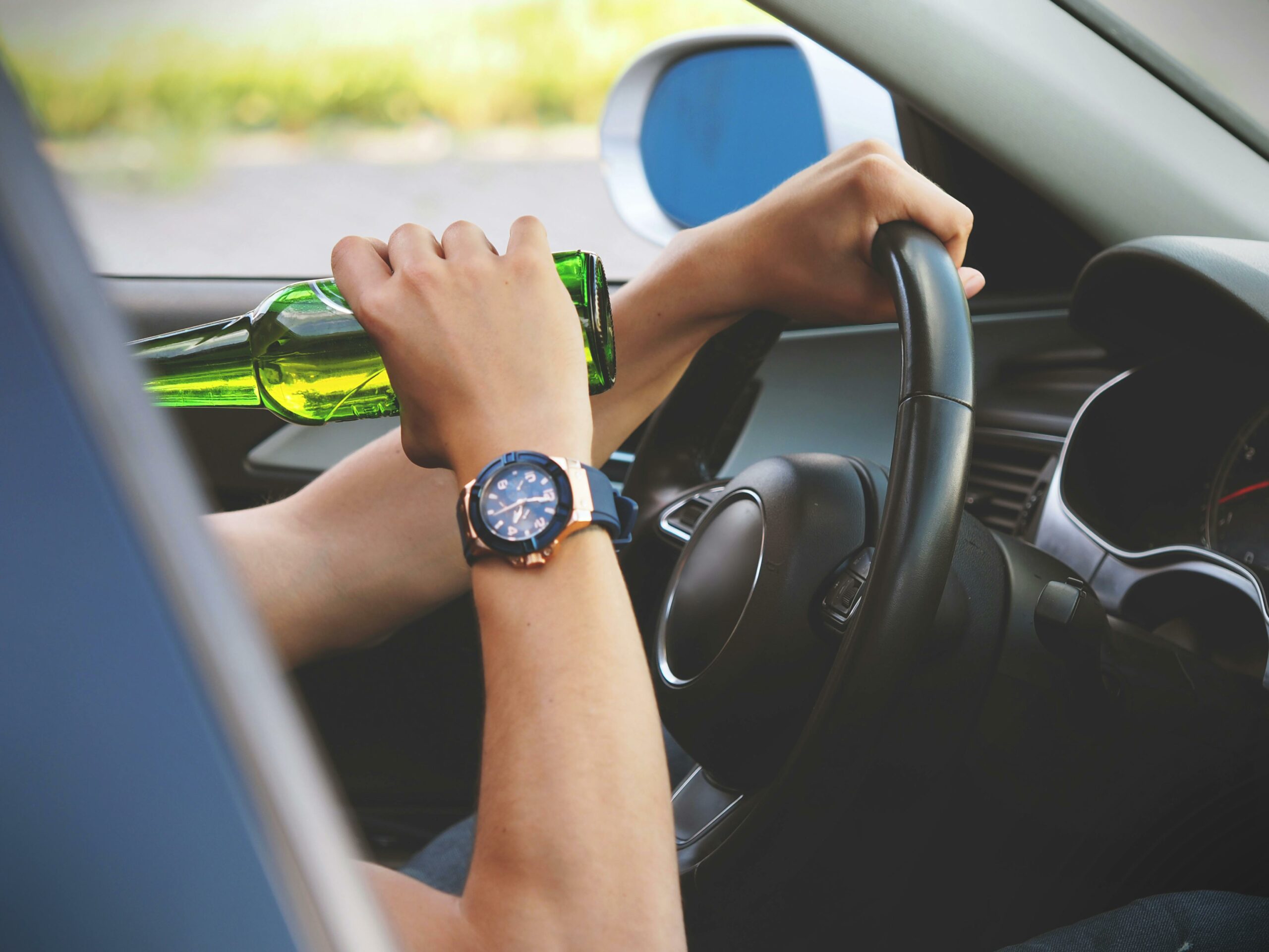 a person holding a bottle of beer while driving