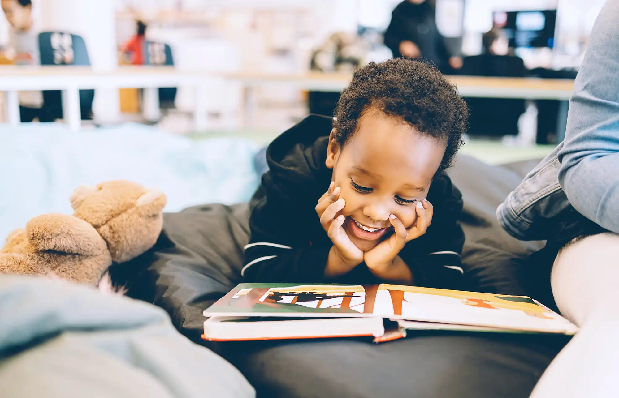 a child lying on a bed reading a book