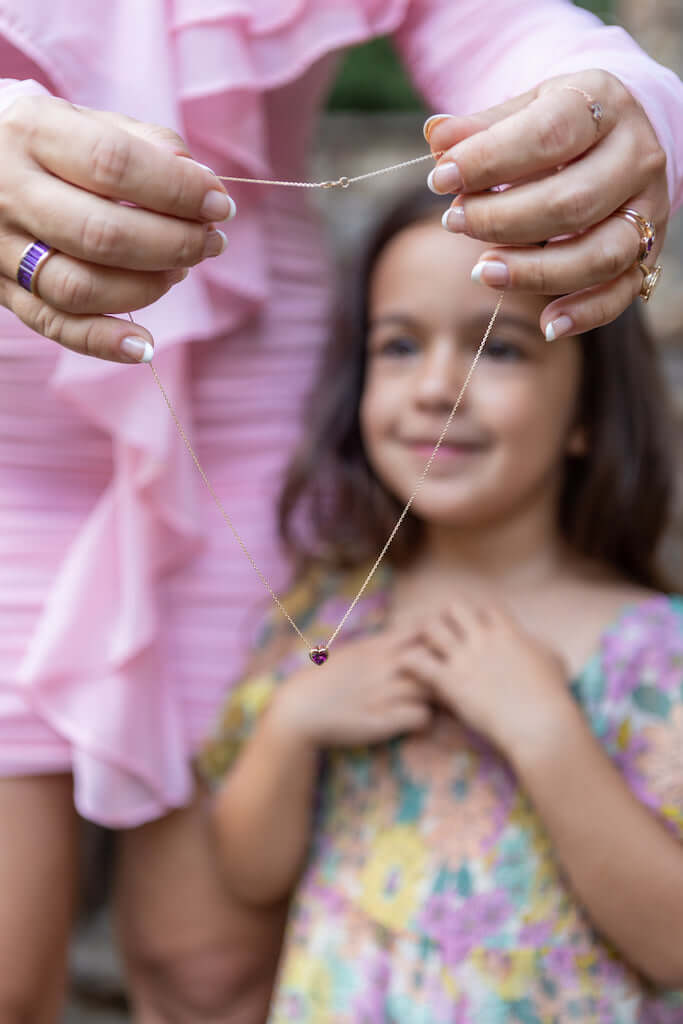 a woman holding a necklace with a little girl in the background