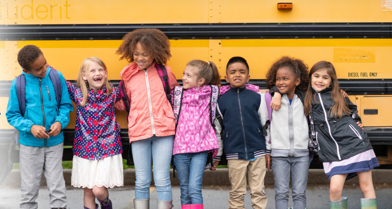 a group of children standing in front of a school bus