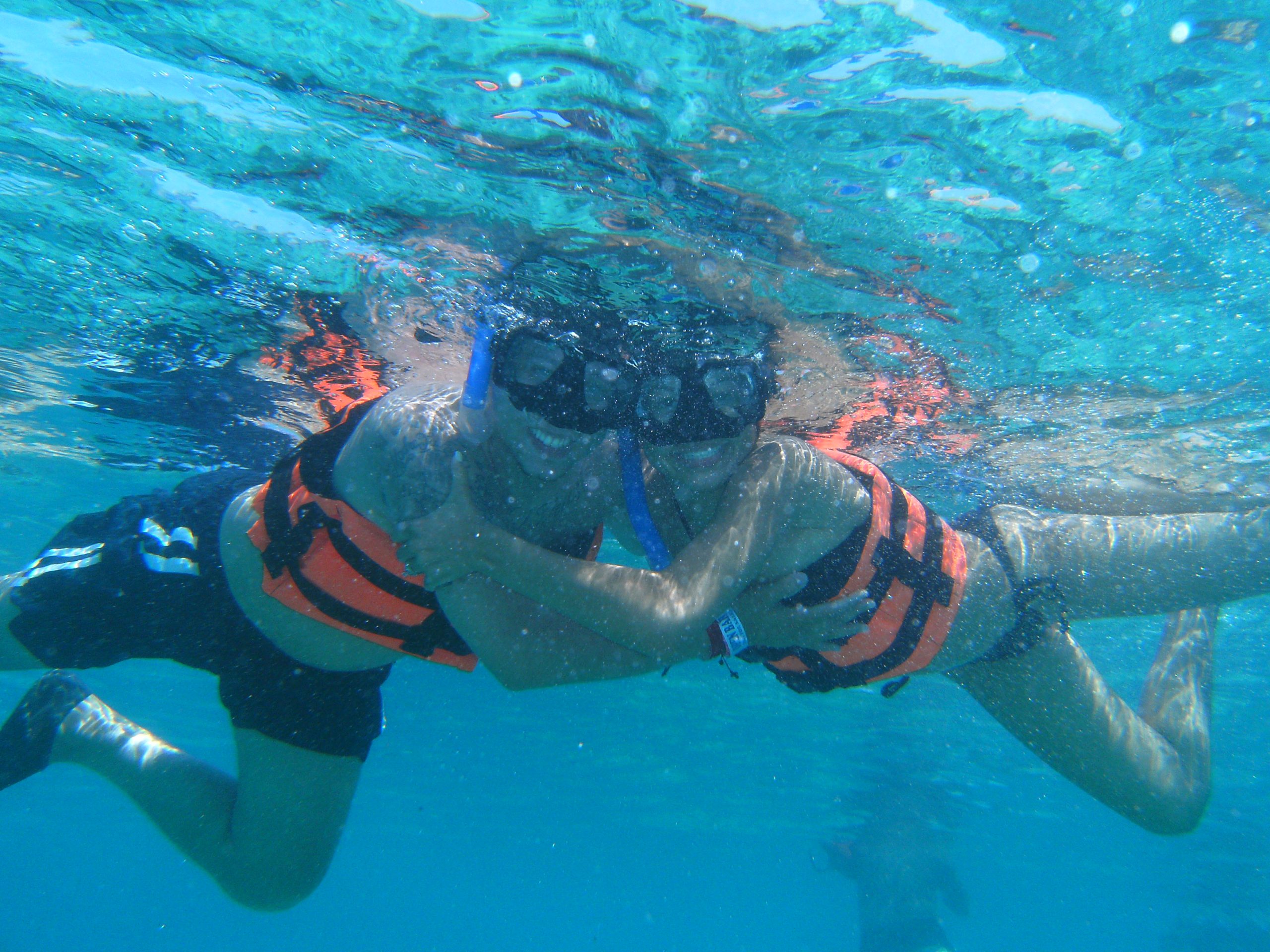 a couple of people wearing life vests and snorkeling underwater