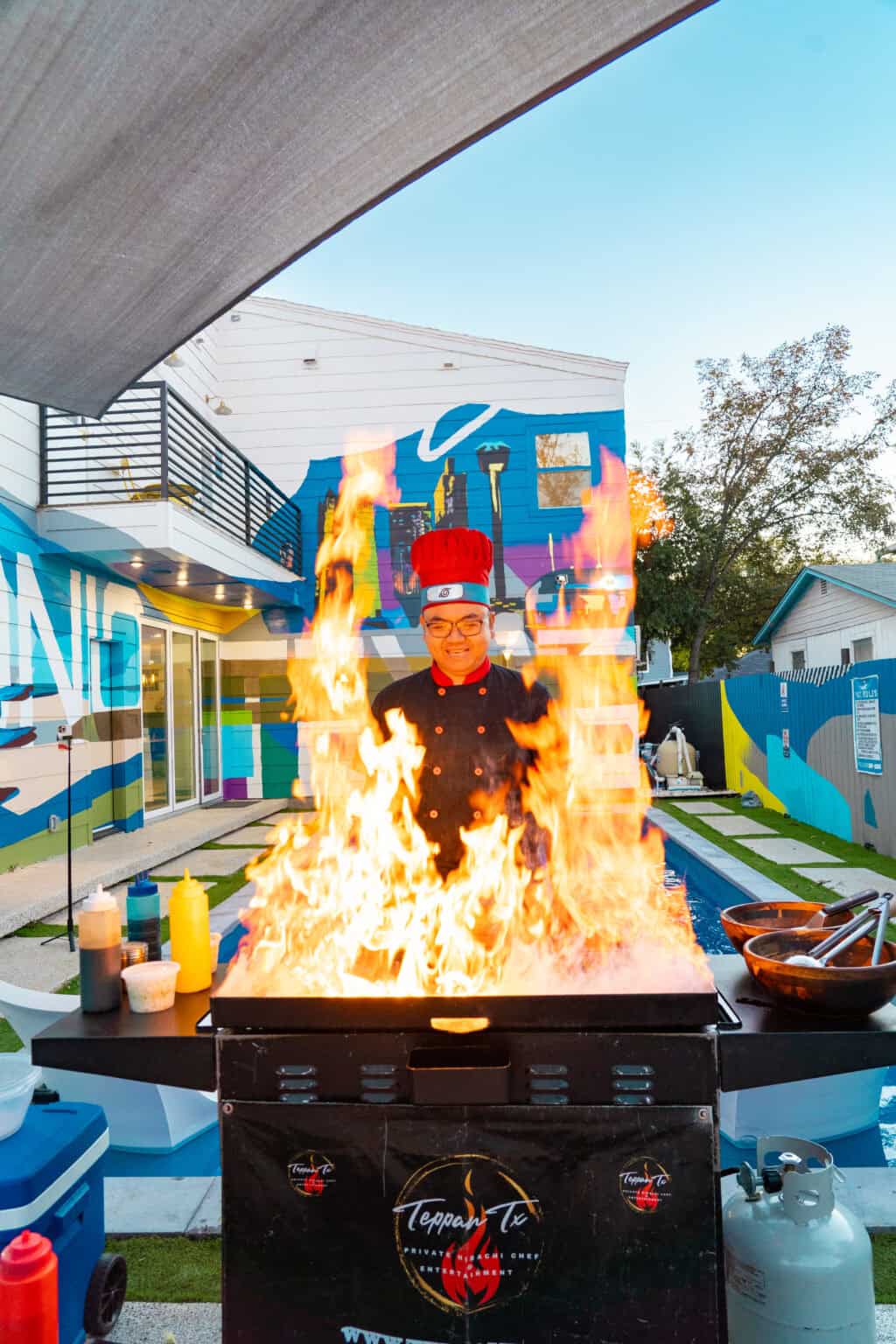a man in a chef uniform standing in front of a fire