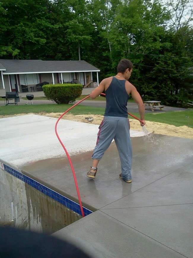 a man spraying a pool with a hose