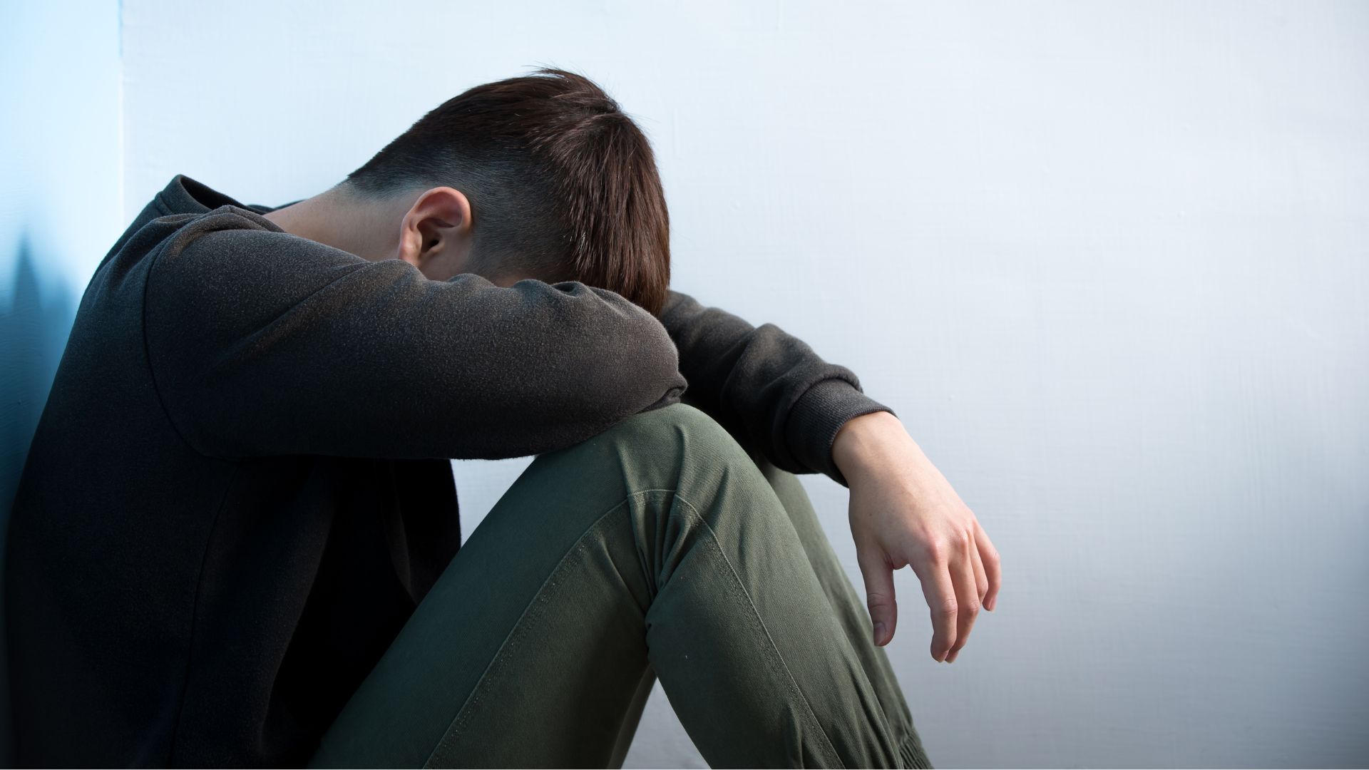 a person sitting down with their head on their knees