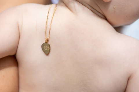 a person's shoulder with a gold necklace