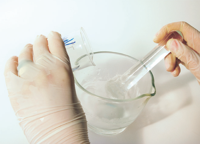 a person holding a beaker with a clear liquid in it