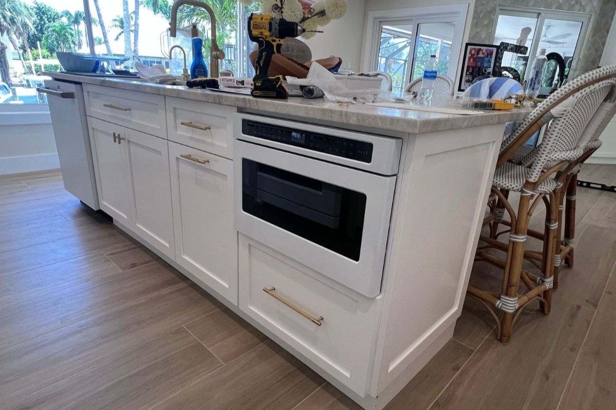 a kitchen with white cabinets and a drill on the counter