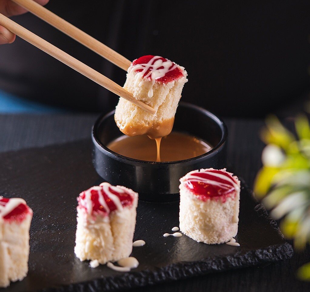 a person holding chopsticks to a plate of sushi