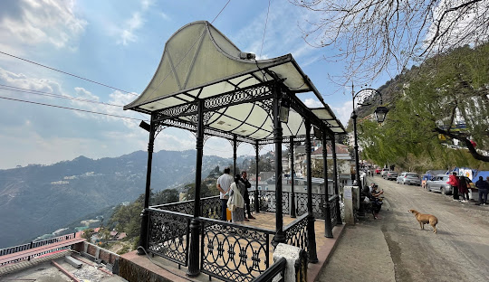 a black metal gazebo with a roof over a hill