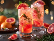 a two glasses of liquid with orange slices and rosemary