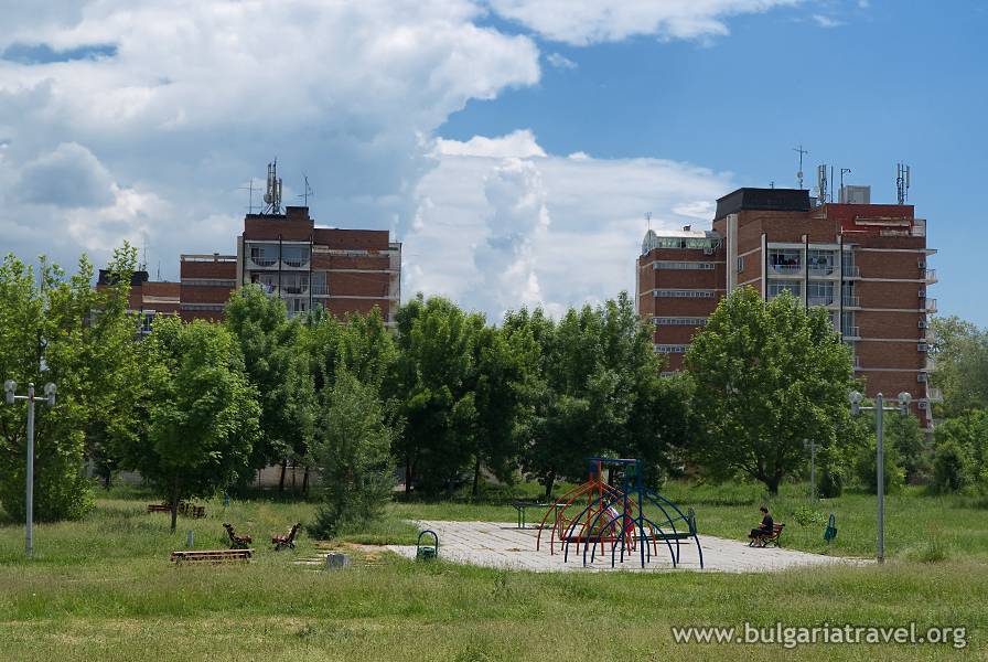 a playground in a park with trees and buildings in the background