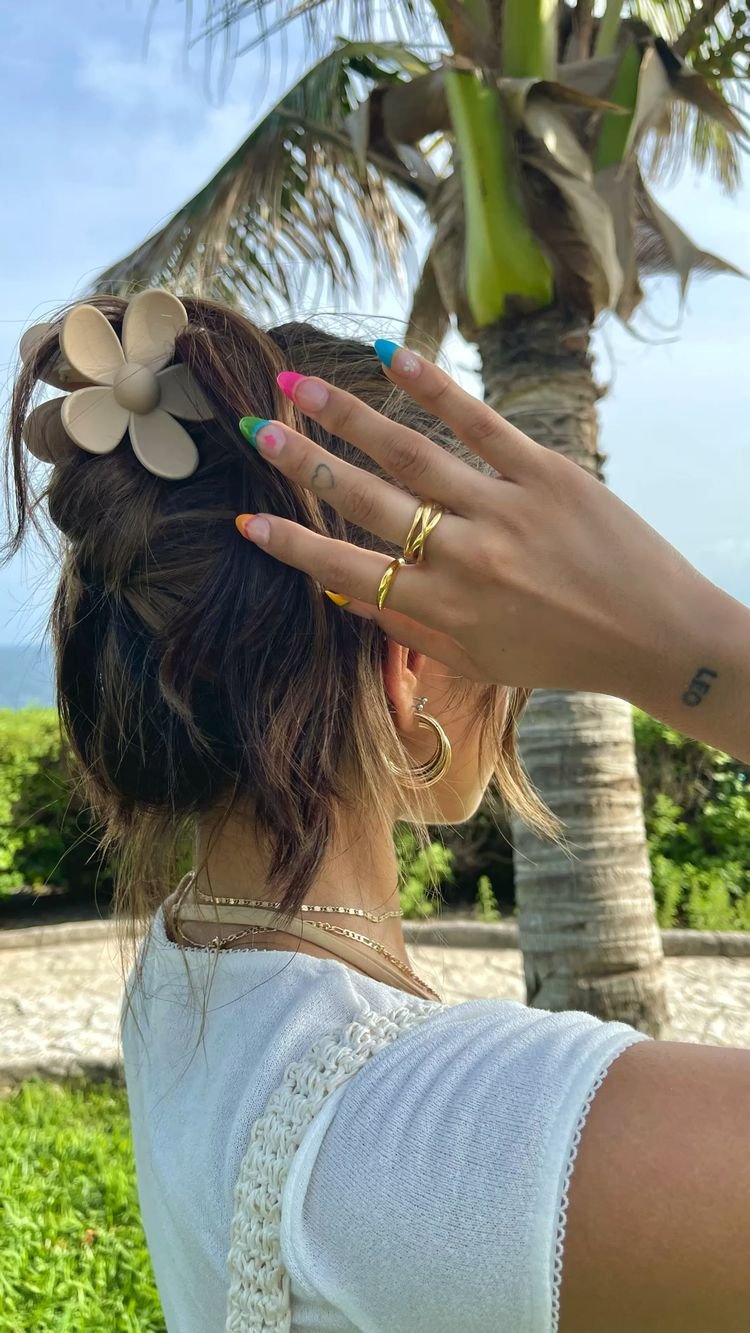a woman with colorful nails and a flower in her hair
