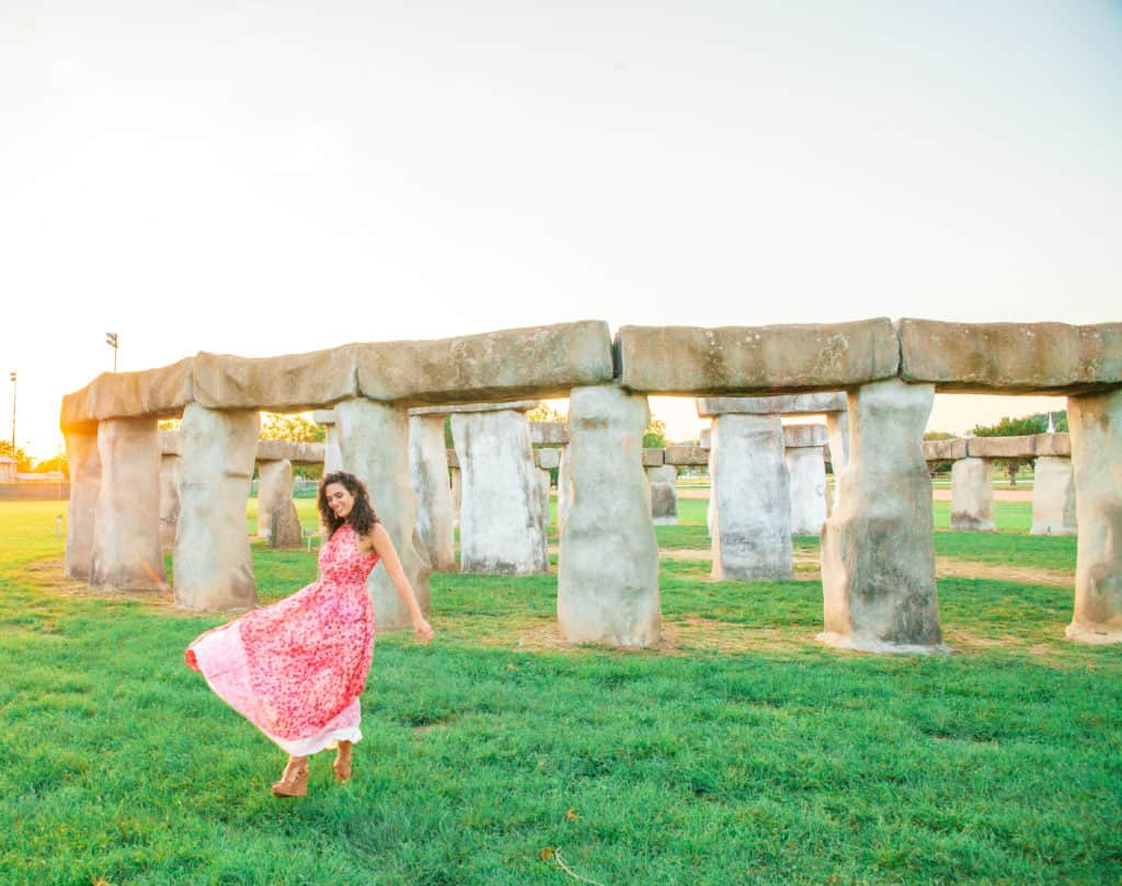 a woman in a dress in front of a stone structure