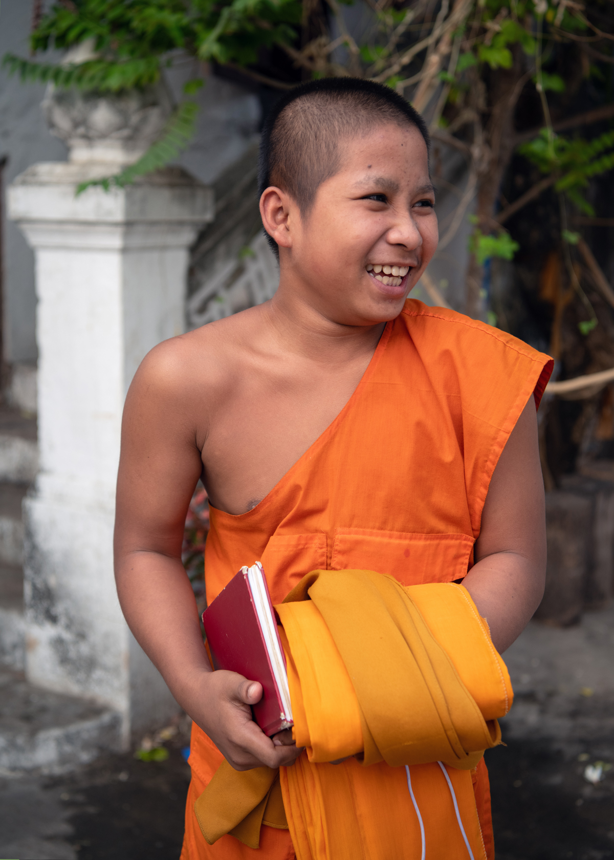 a boy in an orange robe holding a book