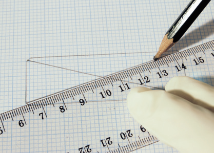 a hand holding a pencil and ruler