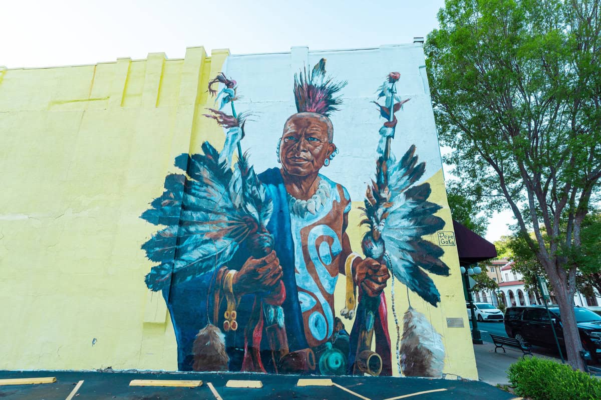 a mural of a man holding feathers