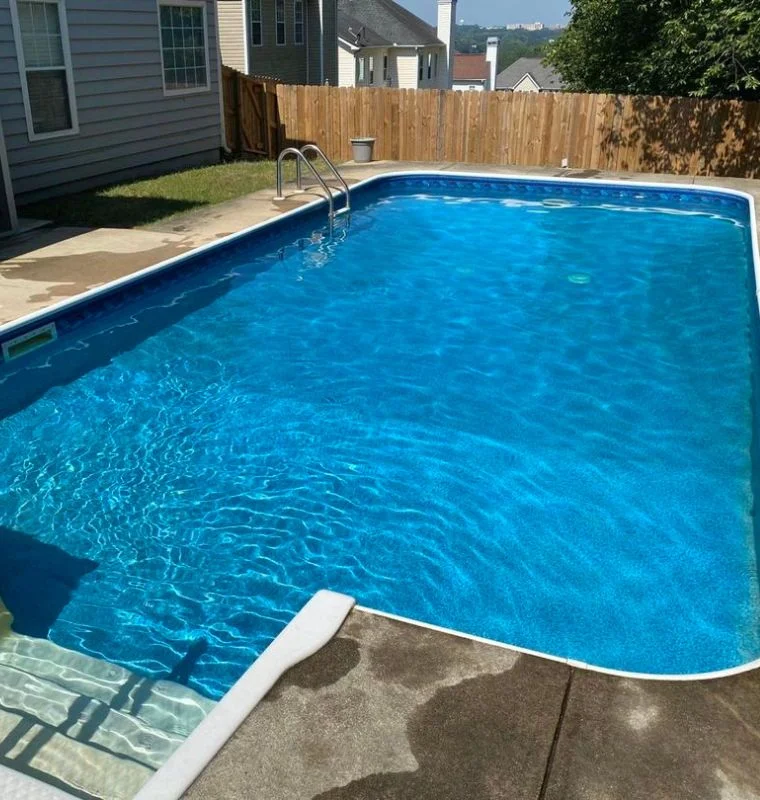 a swimming pool with a fence and a house in the background