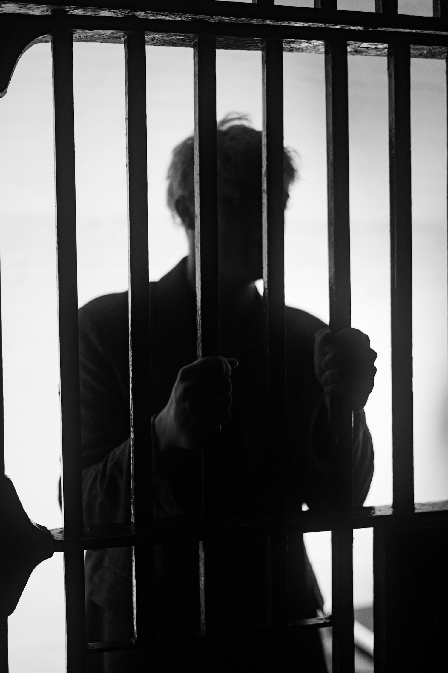 a man behind bars of a jail cell