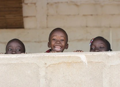 a group of children peeking over a wall