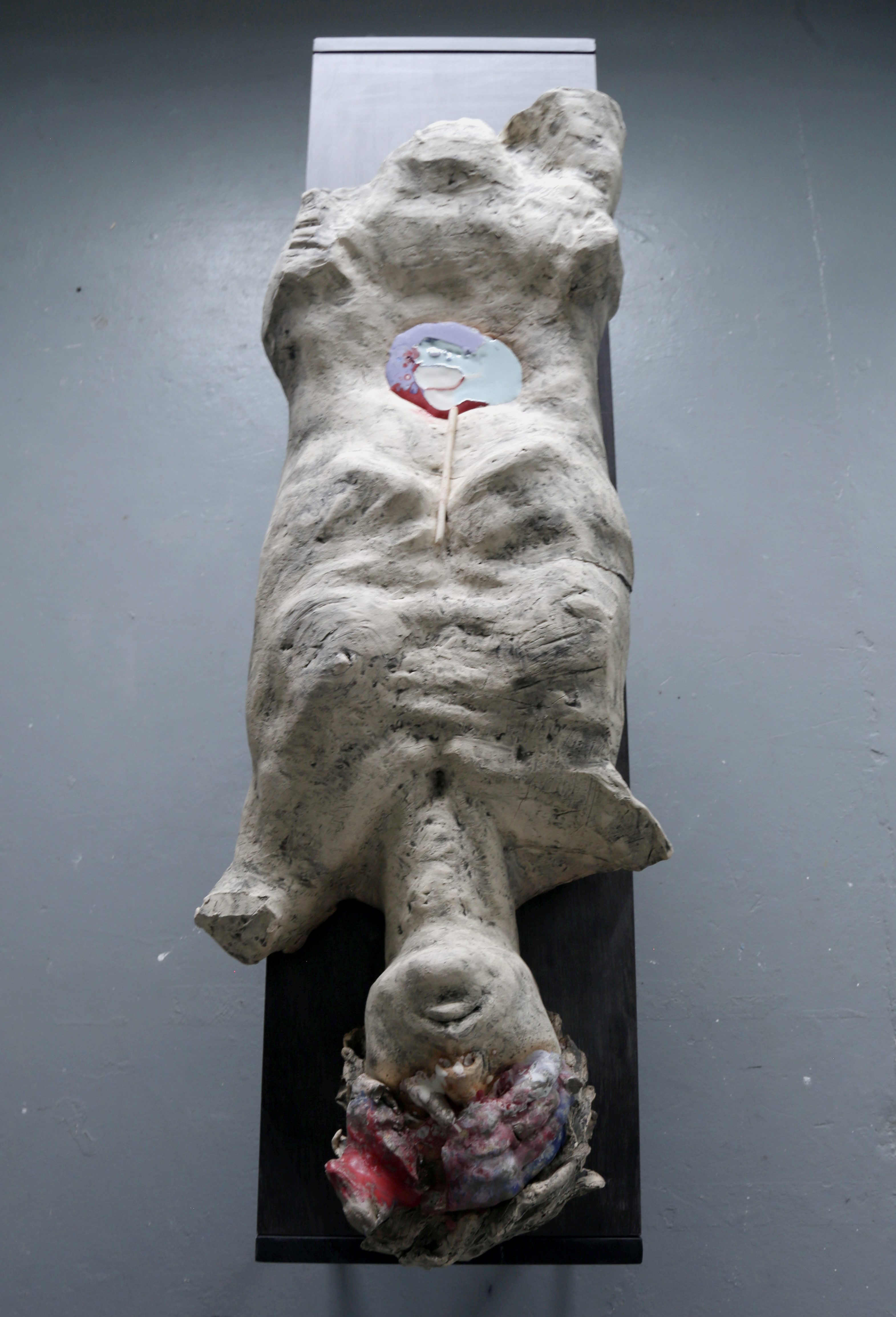 a sculpture of a man lying on a black surface