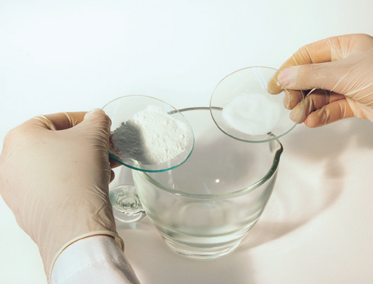 hands holding a pair of round glasses with a white substance in it