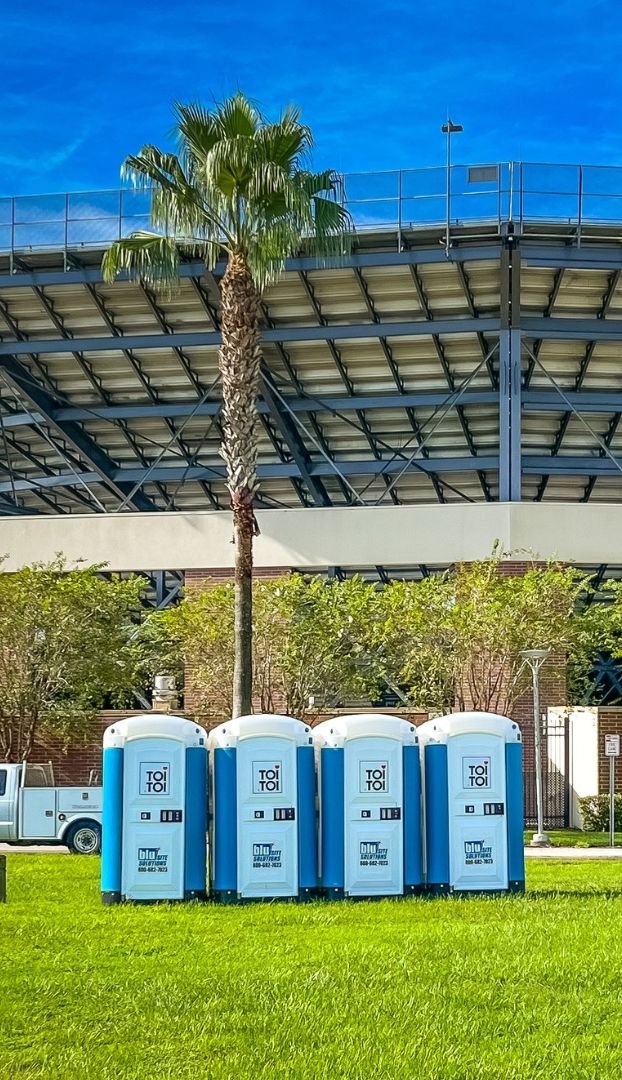 a row of portable toilets in front of a stadium