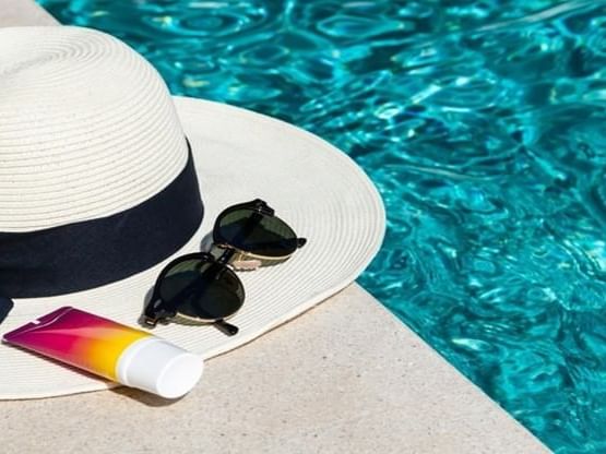 a hat and sunglasses next to a pool