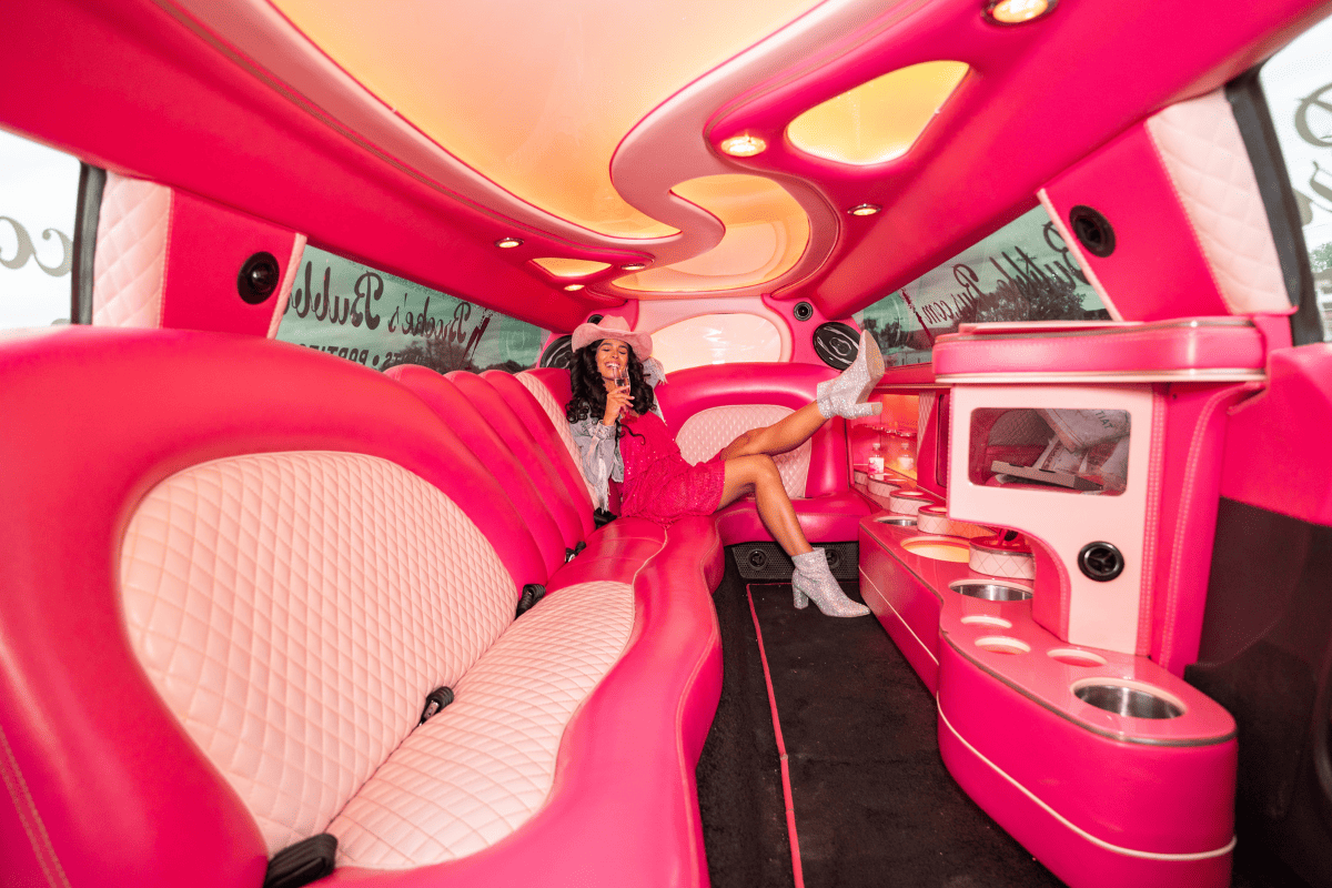 a woman in a pink dress and cowboy hat in a limo