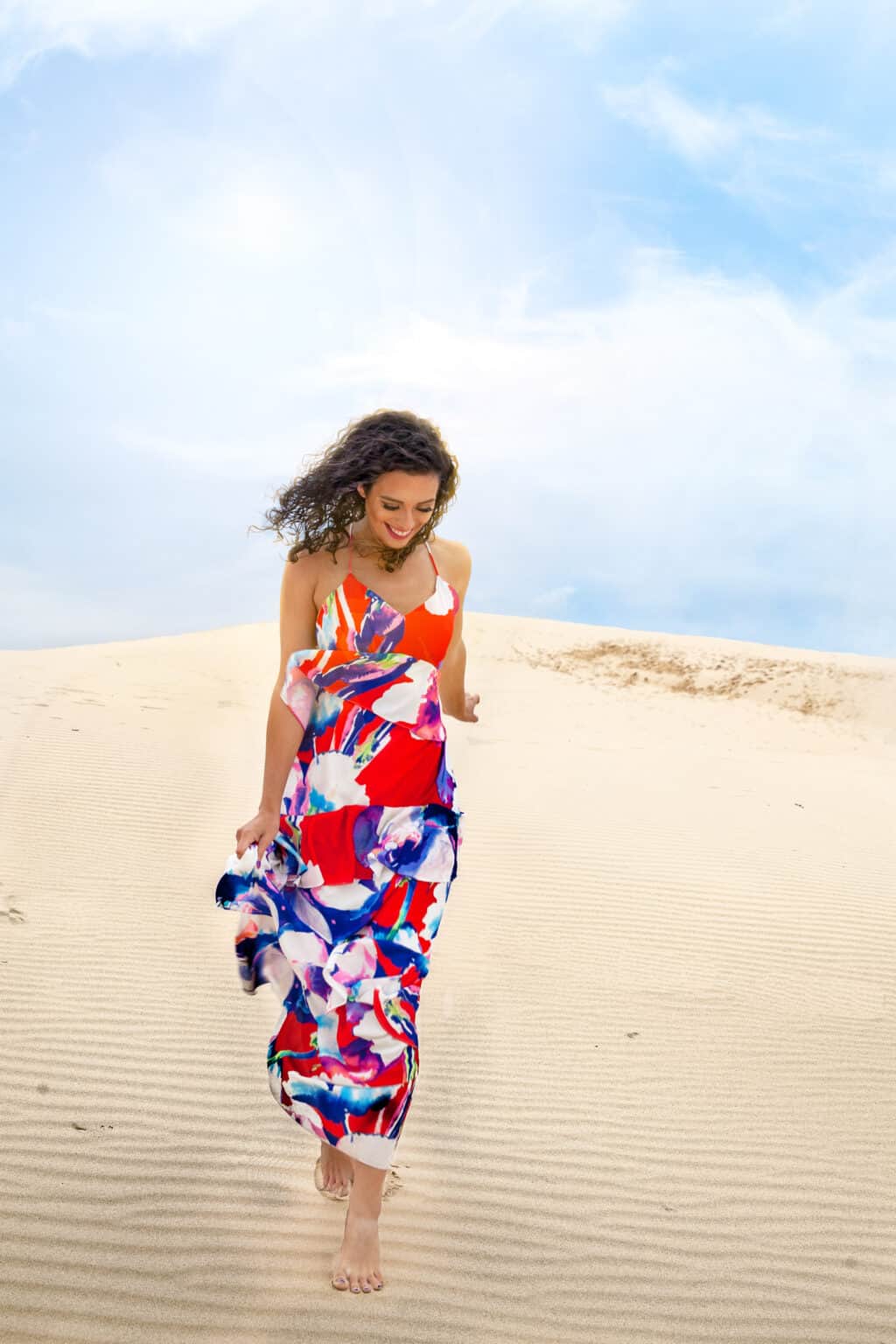 a woman in a dress walking on sand