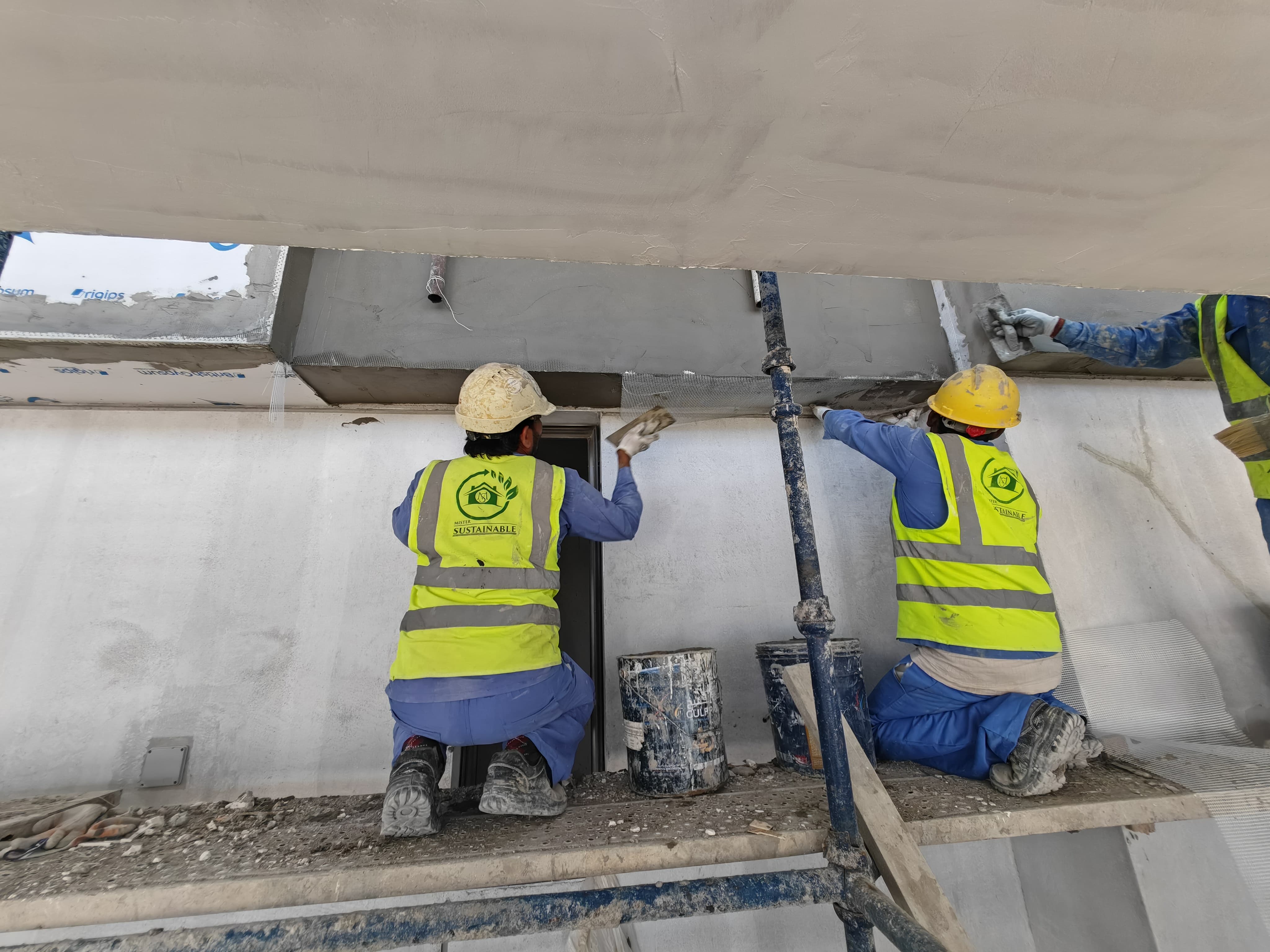 a group of men wearing safety vests and helmets working on a wall