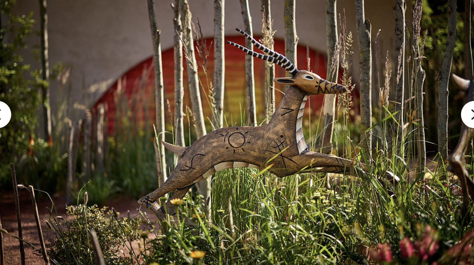 a statue of a deer jumping through tall grass