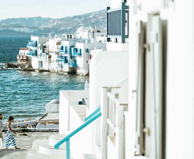 a white building with blue railings and a body of water