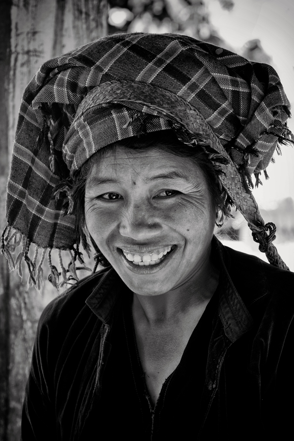 a woman smiling with a plaid headdress