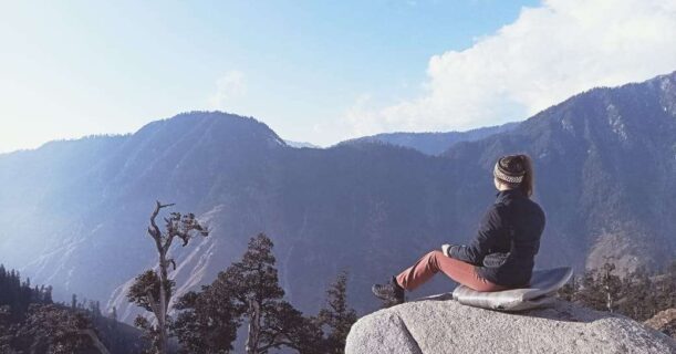 a person sitting on a rock looking at mountains