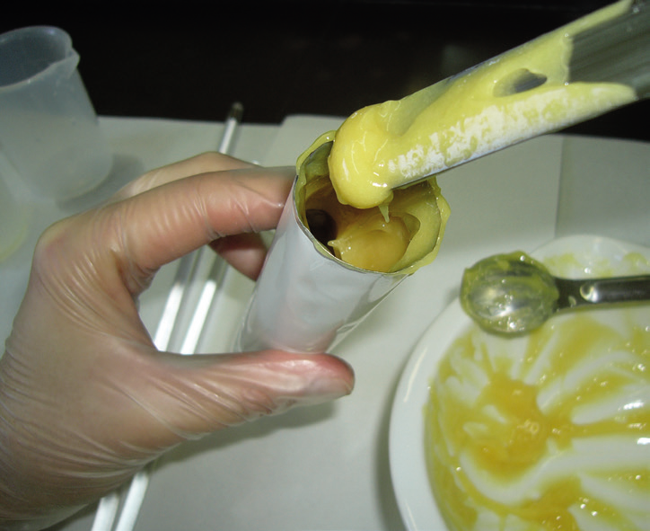 a hand holding a tube of yellow liquid