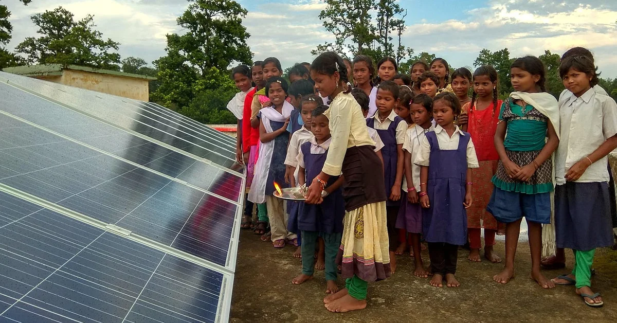 a group of children standing next to a solar panel